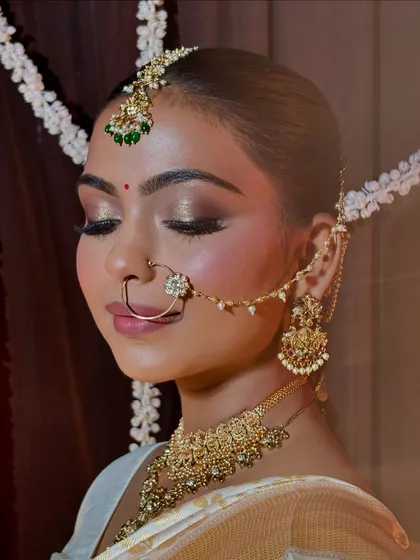 A close-up of Divya's bridal makeup. The golden-bronze eyeshadow and soft pink lips are a perfect combination for her traditional attire.