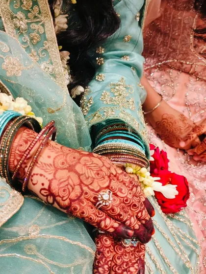 A candid moment from an engagement ceremony, showing off the beautiful henna stain. The deep color of the mehendi looks so rich against the bride's gorgeous outfit.