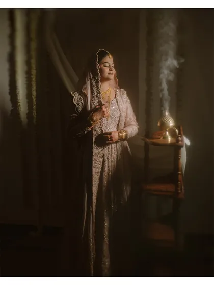 A full-length portrait of the bride during her Nikkah ceremony. The play of light and shadow adds depth and a sense of quiet elegance to the moment.