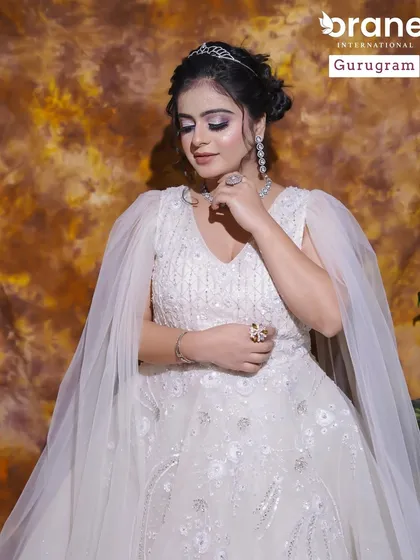 An angelic look in a white gown with a sheer cape. The makeup is soft and shimmery, creating an ethereal and romantic vibe.