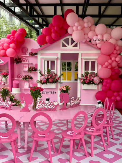 A complete view of the kids' dining area, with Barbie-themed table settings and the playhouse in the background.
