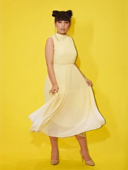 A full-length shot of a model in a flowing yellow dress, part of our "Summer Edit." We offer flat discounts to help you achieve your ultimate summer glow-up.
