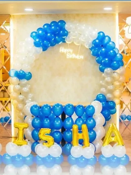 A balloon arch and name decoration in blue, white, and gold. This setup is perfect for a boy's birthday party, creating a festive and personalized photo backdrop.