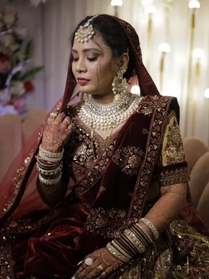 A breathtaking bridal look. This client is wearing a heavy white Kundan and pearl set that perfectly matches her deep red velvet lehenga, creating a royal and timeless aesthetic.
