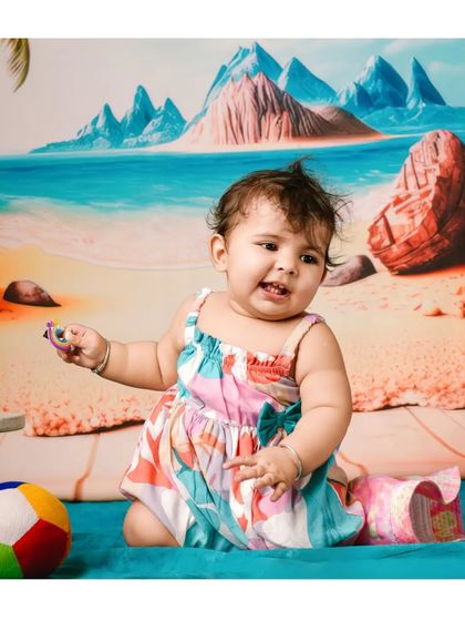 A day at the beach. This fun, themed milestone shoot uses a vibrant beach backdrop to create a playful and imaginative setting for this happy baby girl.