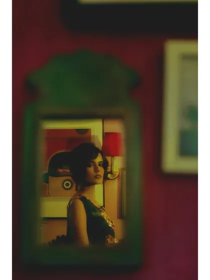 A reflection in a mirror from the 'Room of Memories'. This classic cinematic trope is used to show the character's introspection and the feeling of being an observer in her own life.