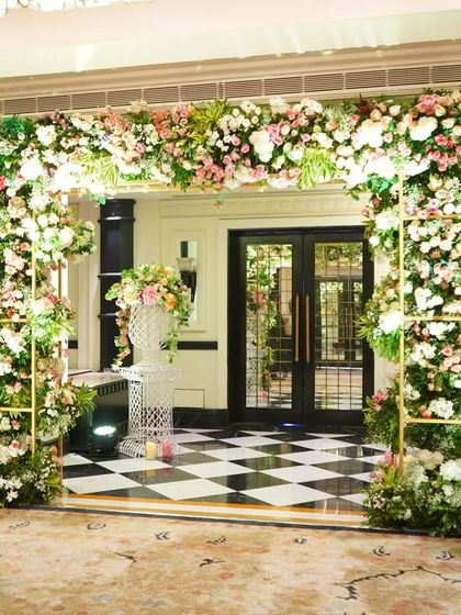 A classic floral entrance with a twist. The arch is made of lush pink and white flowers, set against the striking black and white checkered floor of the ITC Maratha, creating a beautiful contrast.