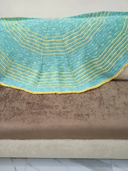 The lime green and yellow shawl spread out on a couch.