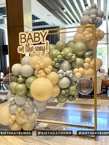 A chic and modern "Baby on the way!" baby shower. The minimalist gold frame is adorned with a sophisticated balloon arrangement in sage green, cream, and grey.