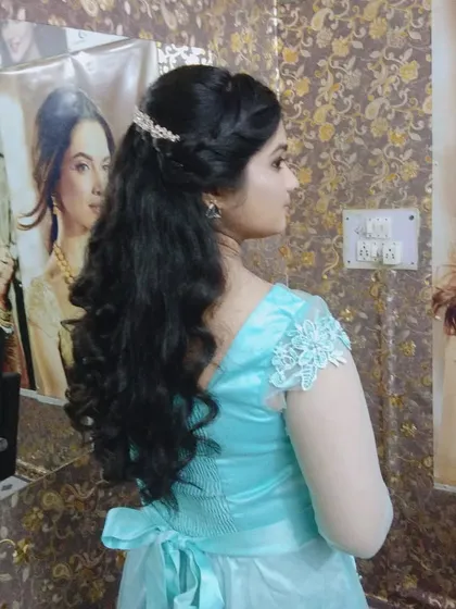 A simple and elegant party hairstyle with soft curls. The hair is pulled back from the face and secured with a delicate accessory, perfect for an evening gown.