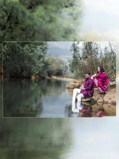 A couple in traditional Marathi attire enjoying a quiet moment by the river, with their reflection in the water.