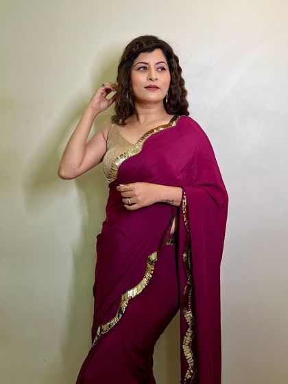 A glamorous pose showing off the modern saree look. The makeup is subtle, with a focus on defined eyes and a neutral lip.