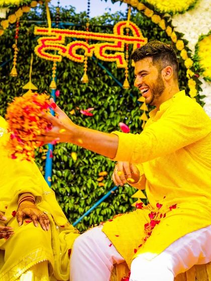 A playful moment where the groom throws a handful of flowers at the bride during their haldi.