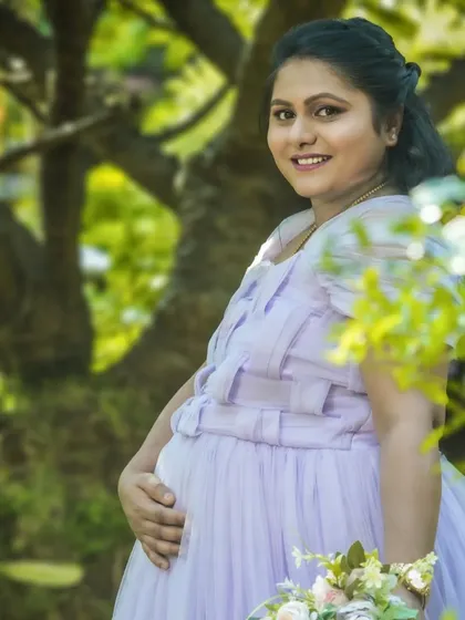 A gentle and warm solo portrait in a sunlit garden. The mom-to-be is holding a small bouquet, adding a delicate and natural touch to the scene.