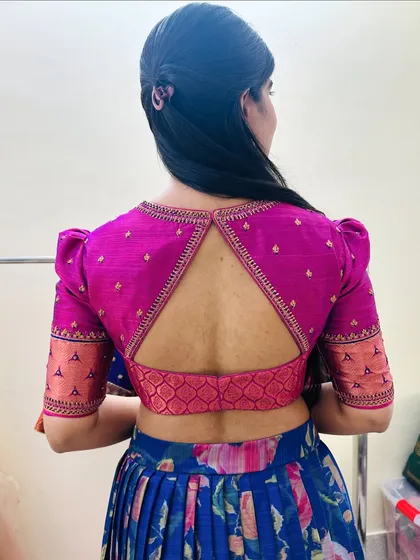 A back view of a client's blouse, featuring puffed sleeves and a triangular keyhole cut-out in a vibrant pink brocade fabric.