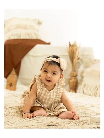 A full-body shot of a baby girl during her sitter session, showcasing her ability to sit up on her own.