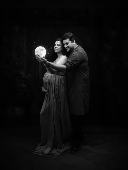 A magical moment captured in black and white. Holding the glowing moon, their faces are illuminated by its light, creating a dreamy and ethereal portrait that feels like a fairytale.