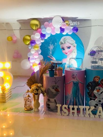 A magical Frozen theme for a 5th birthday party, featuring Elsa, Olaf, and a sparkling balloon arch.