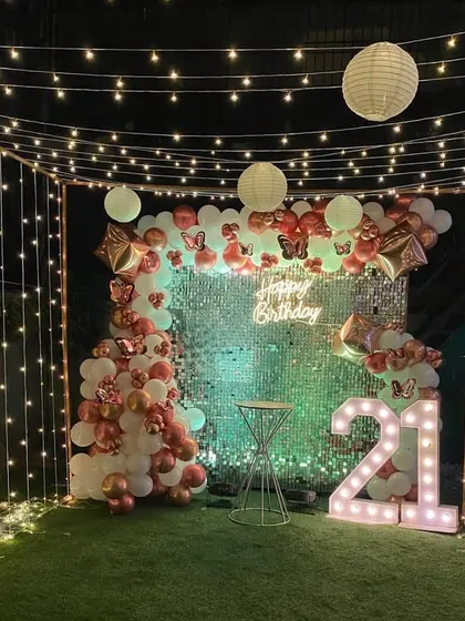 I can transform any terrace into a magical party space. This 21st birthday setup features a full fairy light canopy, a sparkling shimmer wall, and a custom balloon arrangement, creating an unforgettable nighttime ambiance.