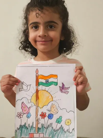 A very happy young artist showing off her completed Independence Day drawing, full of vibrant colors.