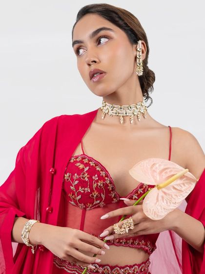 A model looking radiant in our kundan and pearl choker set, paired with a vibrant red contemporary outfit.