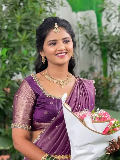 A happy bride at her welcome ceremony. Her purple half-saree is complemented by soft, natural makeup and a simple hairstyle.