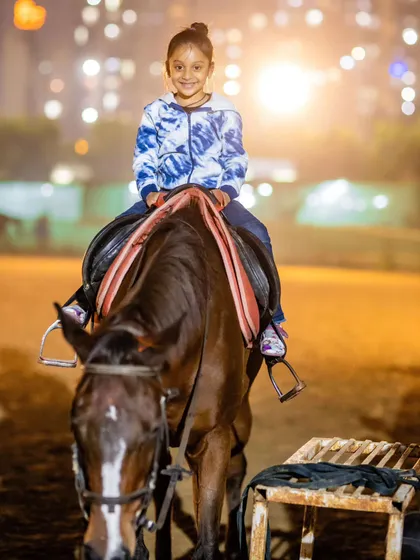 A young girl beams with a happy smile during her evening ride, with the soft lights of the club creating a warm and inviting atmosphere.