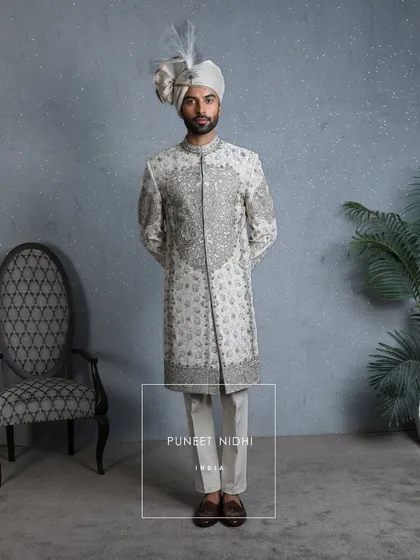 An ivory sherwani brought to life with antique zardauzi, intricate embroidery, and beadwork. The royal grey threads add a regal grace, creating a masterpiece of elegance.