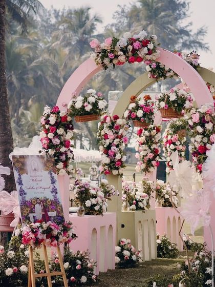 A dreamy pastel Mehendi entrance perfect for a Goa destination wedding. Soft pink and sage green arches are adorned with lush bouquets of pink and white roses, creating a romantic and welcoming beachside vibe.