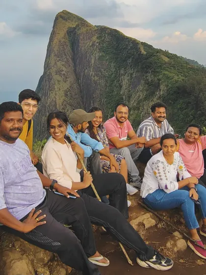 A group relaxing at a viewpoint on the Ettina Bhuja trek, with the distinctive peak in the background.