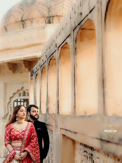 A serene and stylish pre-wedding portrait against the warm, textured walls of a Jaipur fort. Their calm expressions and the historic setting create a beautiful contrast.