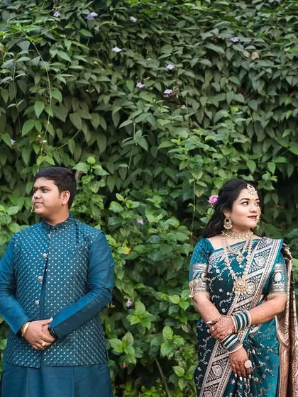 This portrait showcases a more formal, yet relaxed, pose. The couple stands against a rich green backdrop, their coordinated blue outfits creating a visually pleasing harmony. It's a modern take on a traditional couple portrait.