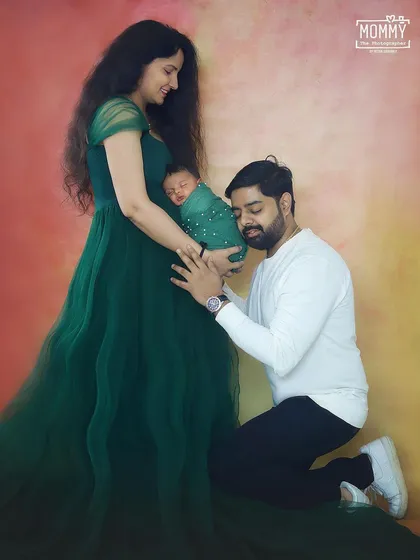 A beautiful and creative pose showing the connection between a maternity photo and a newborn photo. The father lovingly looks at the baby held against the mother's tummy, where the baby was just a short time ago.