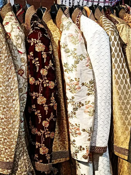 A close-up of the sherwani rack, showcasing a variety of colors and embroidery styles, including rich velvet, classic gold, and floral patterns.