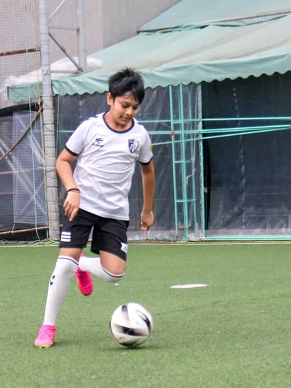 A young footballer practices dribbling, focusing on keeping the ball close to his feet for maximum control and agility.