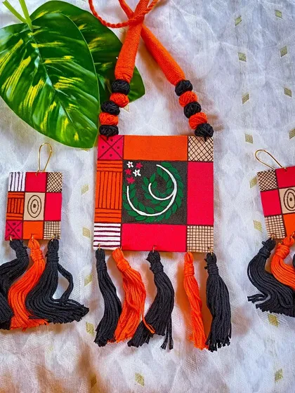 For those who love bold, geometric designs, this set features a patchwork of hand-painted patterns on fabric. The vibrant orange and red are balanced by black and white details, with thread tassels adding texture and movement. This is a contemporary take on handcrafted jewelry.