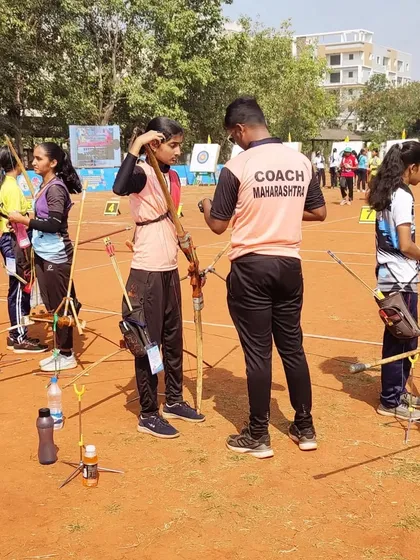 A great coach makes all the difference. During a competition, I take the time to give last-minute advice and encouragement to one of our young archers, ensuring she feels supported and ready.
