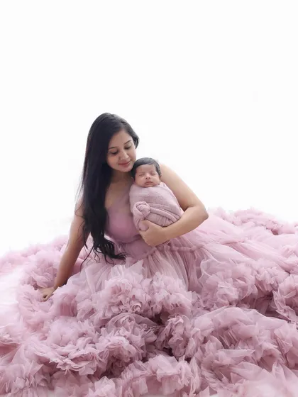 Wrapped in a cloud of tulle. This shot showcases the mother's stunning gown, which creates a soft, dreamy frame around her and her swaddled newborn. It's a beautiful blend of maternity and newborn photography.