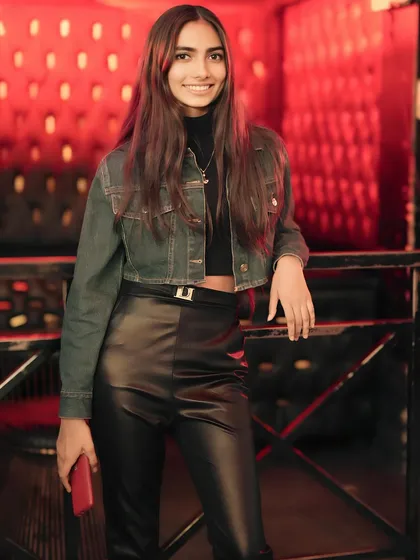 A guest in a stylish outfit, posing by the red-lit lounge area.