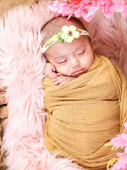 A 10-day-old newborn sleeping peacefully, surrounded by pink flowers. The first two weeks are the ideal time for these sleepy, posed shots.