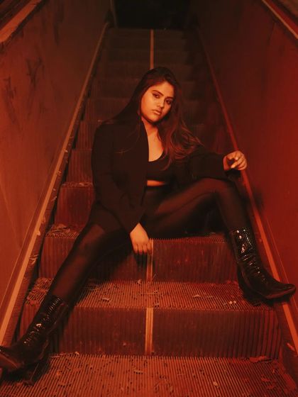 Another shot from the same series, showing a different seated pose. The consistent red lighting and gritty location tie this set together beautifully.