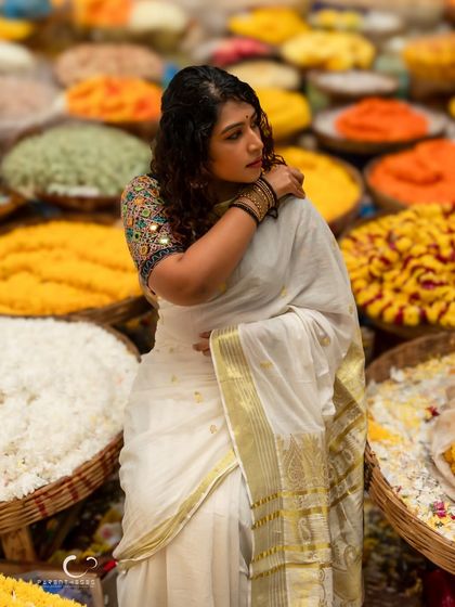 A stunning portrait set in a vibrant flower market. The colors of the flowers create an incredible backdrop for her elegant white and gold saree.