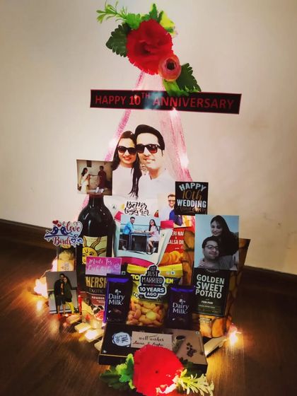 This 10th-anniversary canopy hamper is both elegant and romantic. It features a bottle of wine, snacks, and personal photos, all enclosed within a delicate, light-up canopy structure.