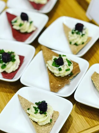 Sour cream and chive dip served on crispy multigrain crackers, garnished with fresh blackberry for a touch of sweetness.