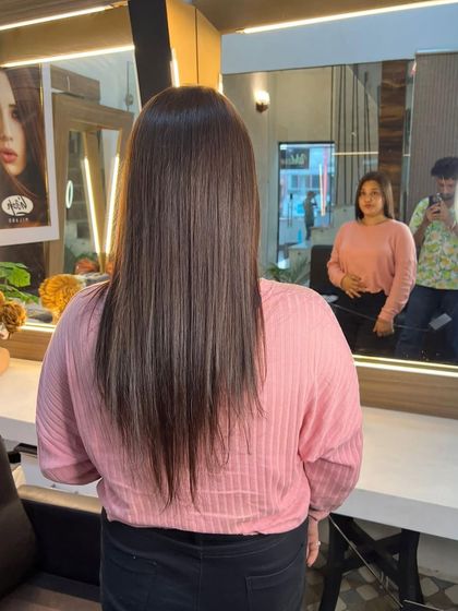 A client admiring her fresh haircut and color in the mirror. The style is straight with a slight inward curve.