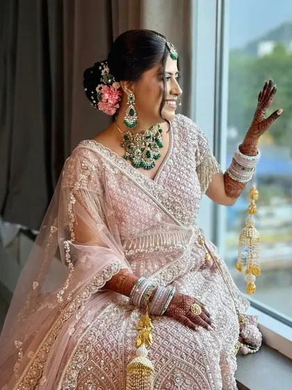 A joyful bride by the window, her kalire adding to the traditional charm. Her happiness is the most beautiful part of this look.