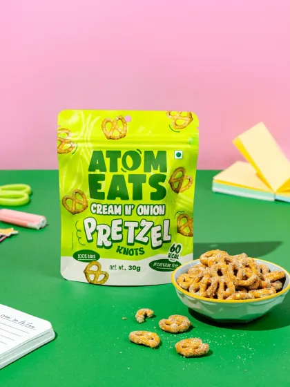A clean, minimalist shot of Atom Eats Cream 'n' Onion pretzels with a bowl of the snack against a split-tone background. This is great for e-commerce listings and clear product showcases.