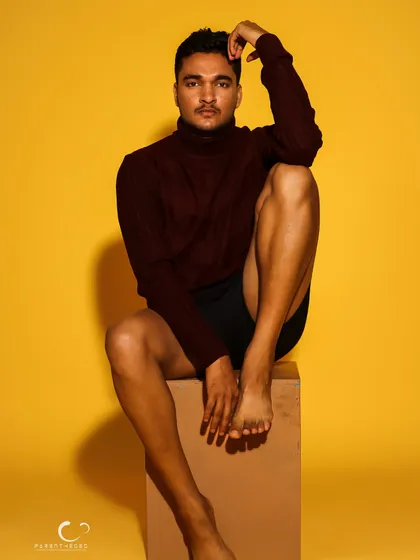 A minimalist portrait focusing on form and physique. The simple styling and confident pose against the yellow background create a powerful, artistic statement.