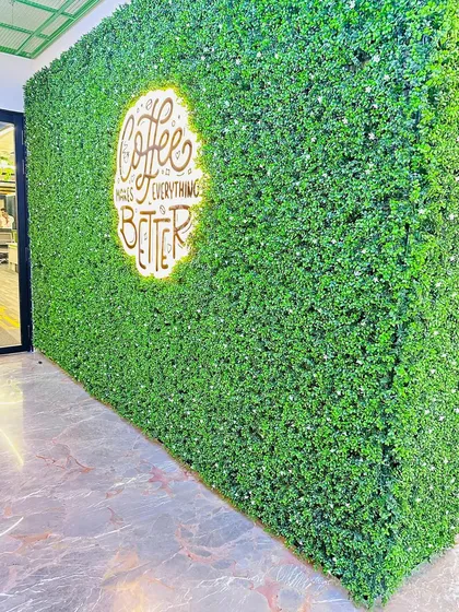Your brand can be part of the design. For this cafe, we embedded a backlit logo directly into the artificial green wall, creating a vibrant and welcoming feature wall that strengthens the brand's identity.