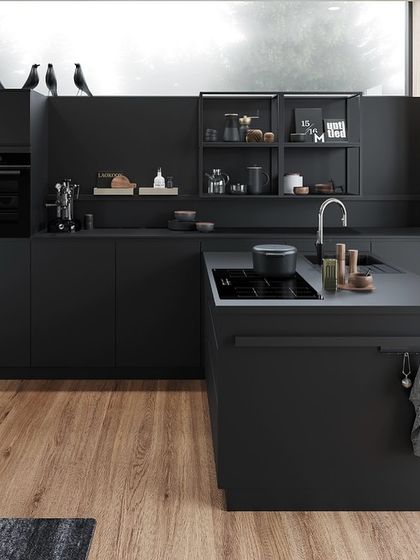 This wide shot shows how the all-black kitchen, paired with a warm wood floor, creates a chic and inviting space that feels both modern and comfortable.